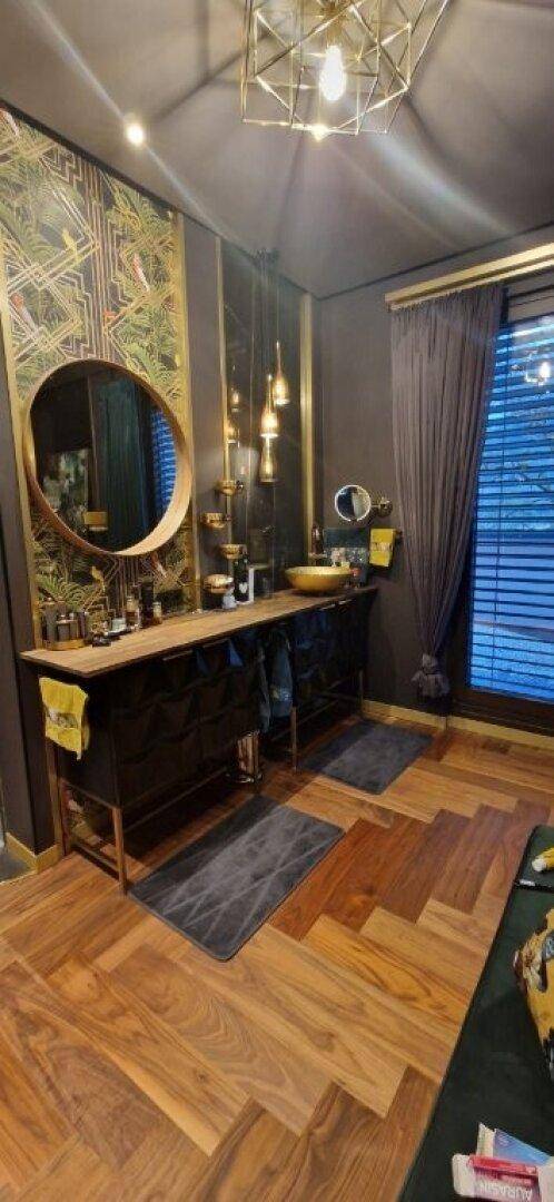 Elegantes Badezimmer mit Doppelwaschbecken, rundem Spiegel und Fischgrätparkett.