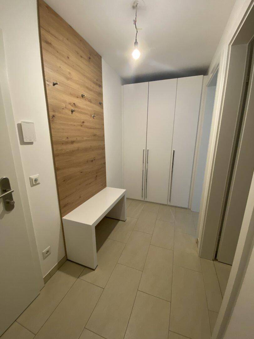 Eingangsbereich mit Garderobe, Sitzbank und integrierten weißen Einbauschränken für Stauraum.