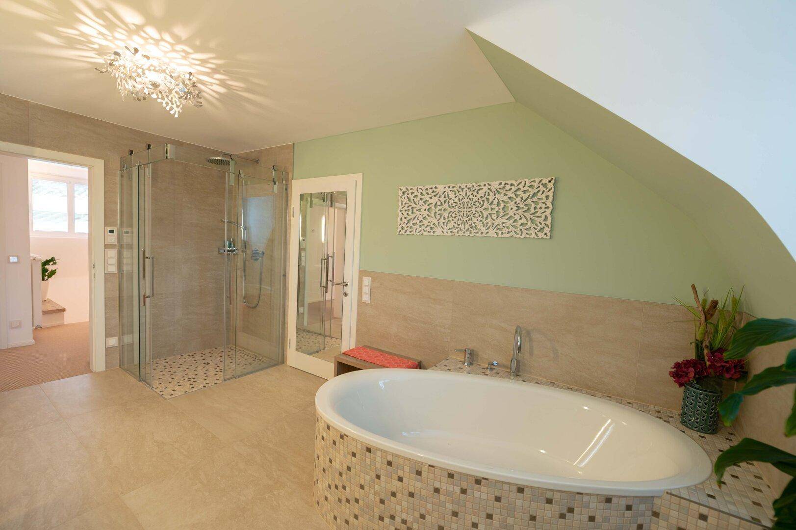 Geräumiges Badezimmer mit freistehender Badewanne, begehbarer Dusche und Dachschräge, hell gefliest.