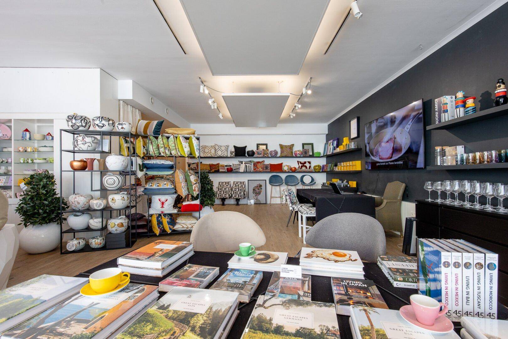 Geräumiger Verkaufsraum mit Auslagen von Büchern und Wohnaccessoires, unterstrichen durch moderne Beleuchtung.