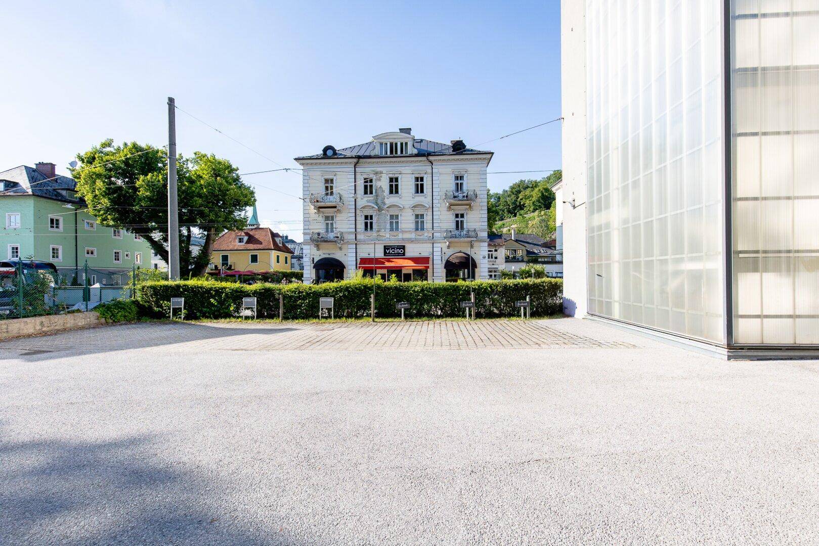 Außenansicht eines Parkplatzes mit einem traditionellen Gebäude im Hintergrund unter blauem Himmel.