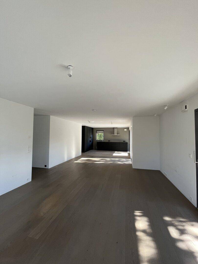 Geräumiger, offener Wohnbereich mit dunklem Holzboden und Blick auf die moderne Küche.