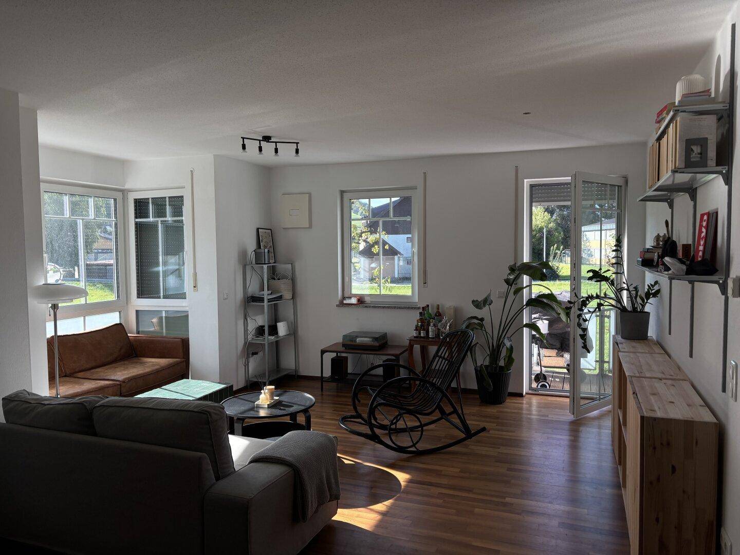 Helles Wohnzimmer mit Holzboden, gemütlichen Sofas und Blick ins Grüne durch große Fenster.