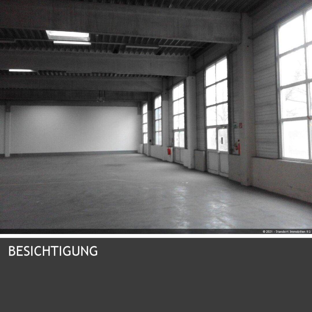 Leere Industriehalle mit hohen Decken, großen Fenstern und Betonboden, bereit zur Besichtigung.