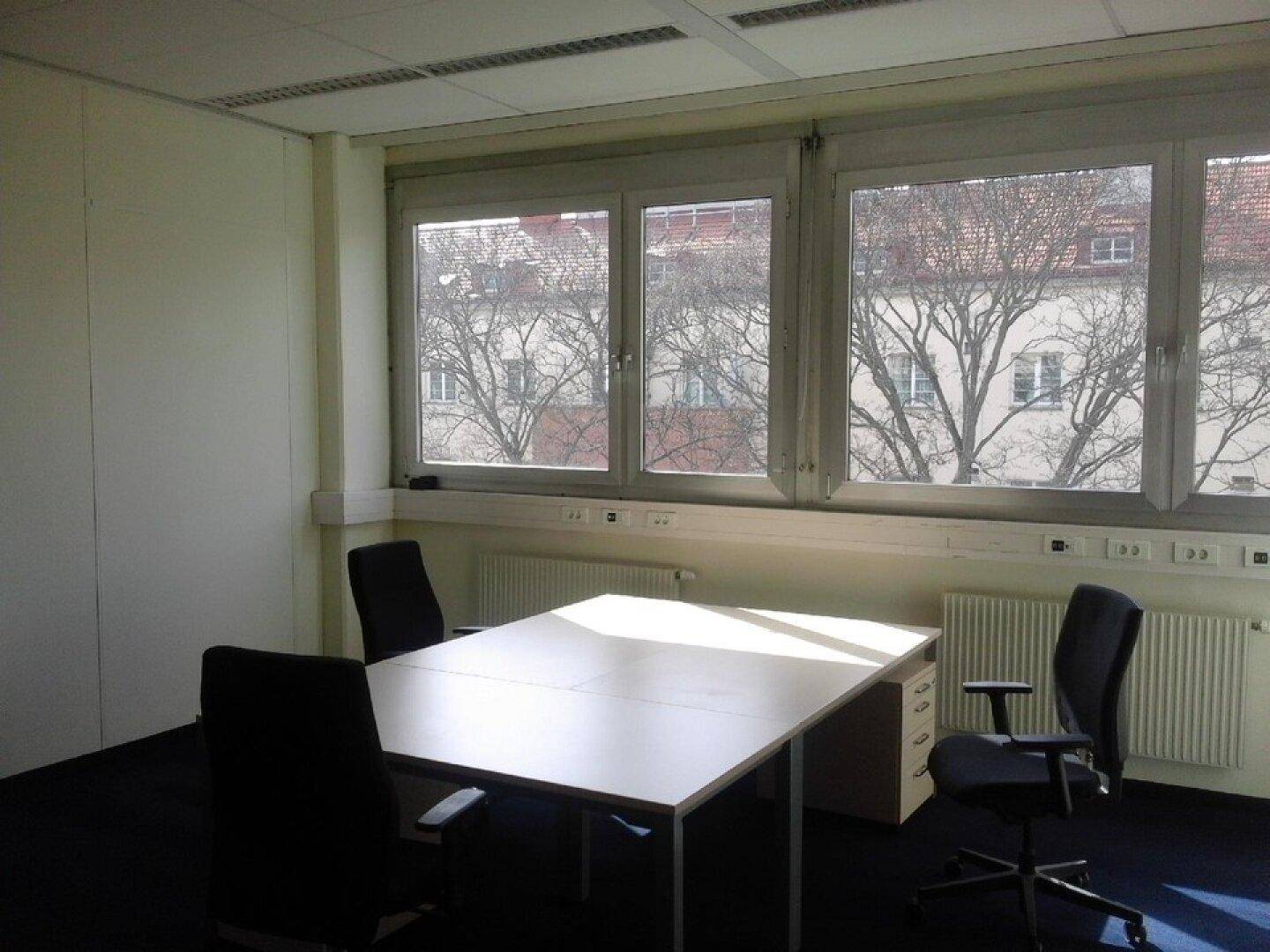 Büro mit viel Tageslicht, Teppichboden und Blick auf die Nachbarschaft, ideal für eine helle Arbeitsumgebung.