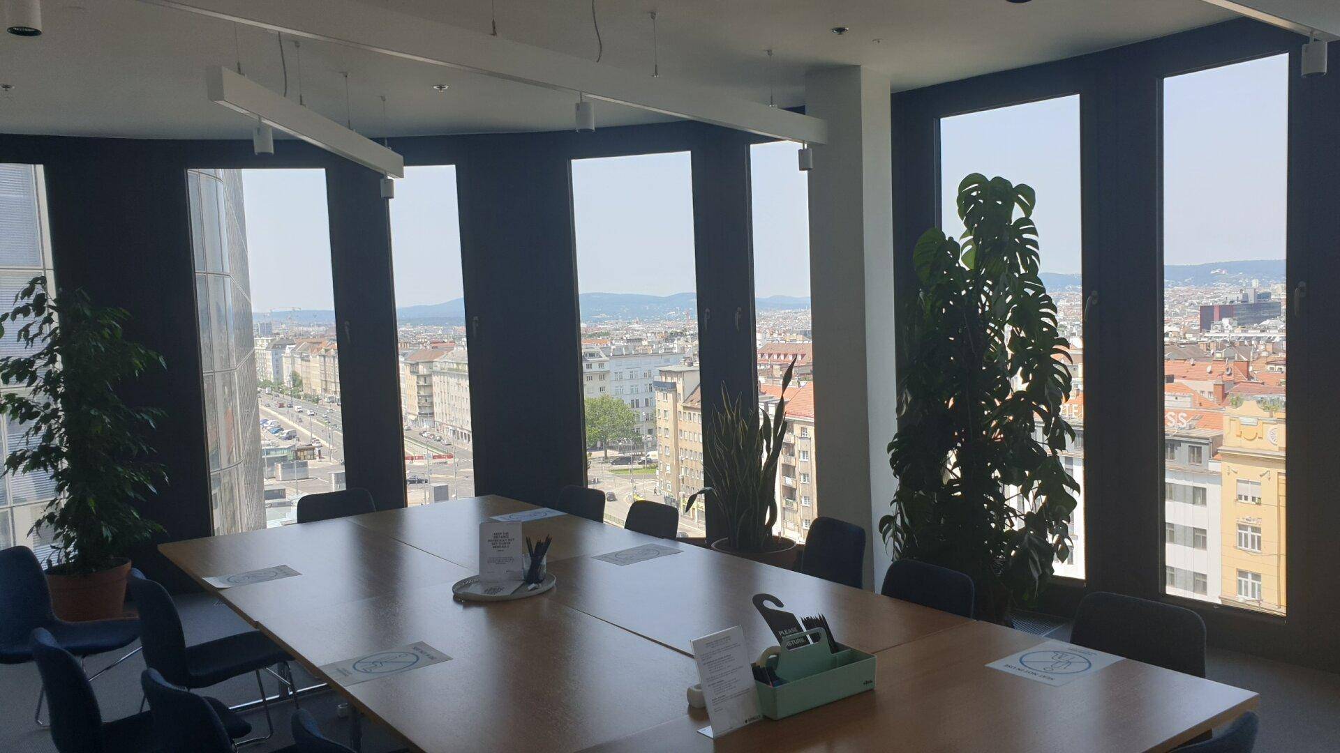 Großer Konferenzraum mit langem Tisch und Stühlen, bietet einen weiten Blick über die Stadt.