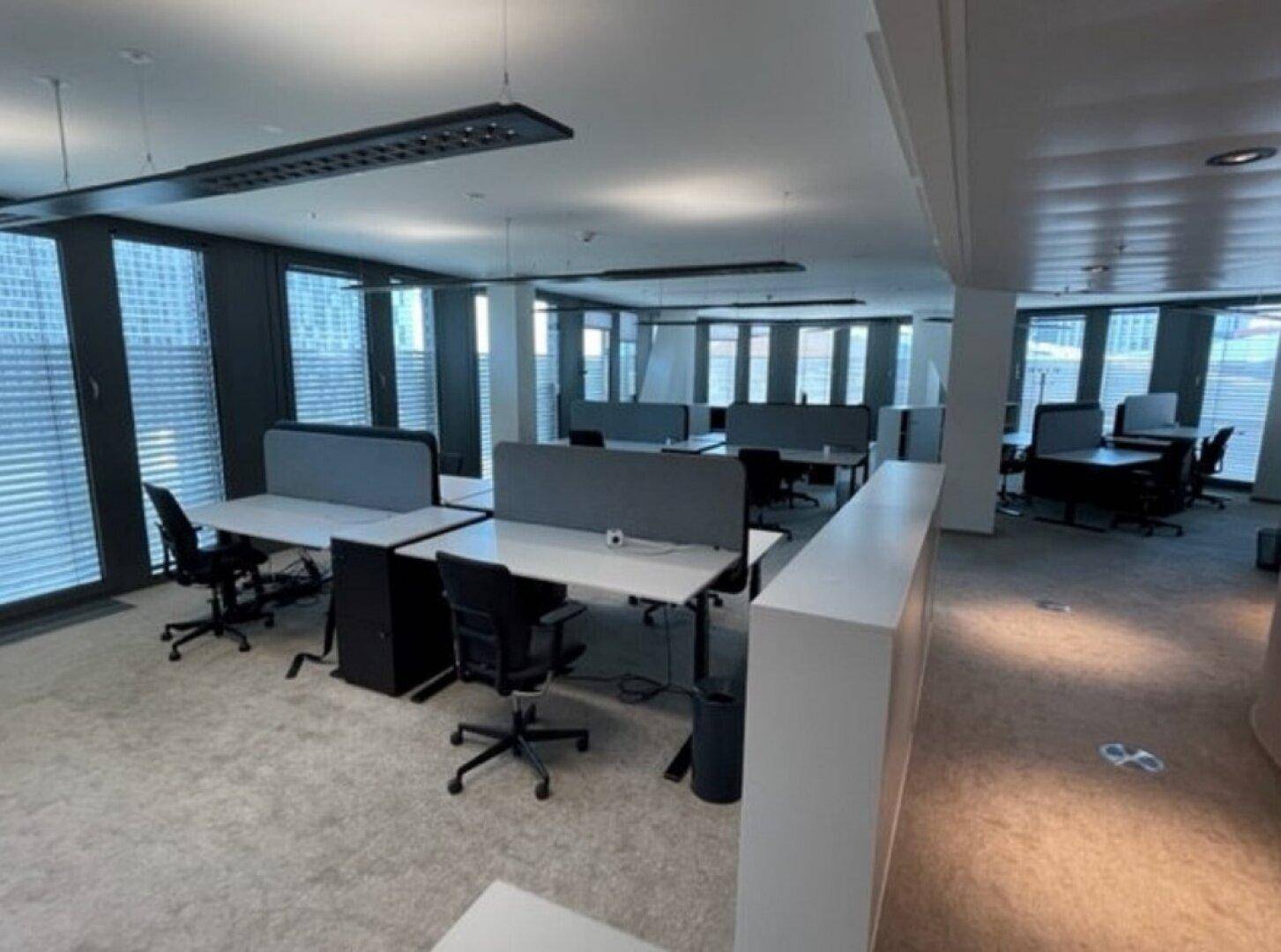 Helles und modernes Großraumbüro mit ergonomischen Stühlen und vielen Arbeitsplätzen.