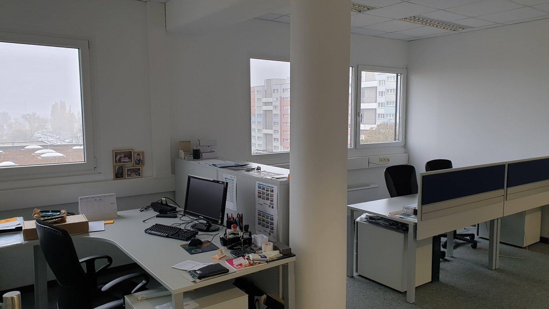 Geräumiges Büro mit mehreren Arbeitsplätzen, Computern und großen Fenstern mit Blick auf die Umgebung.