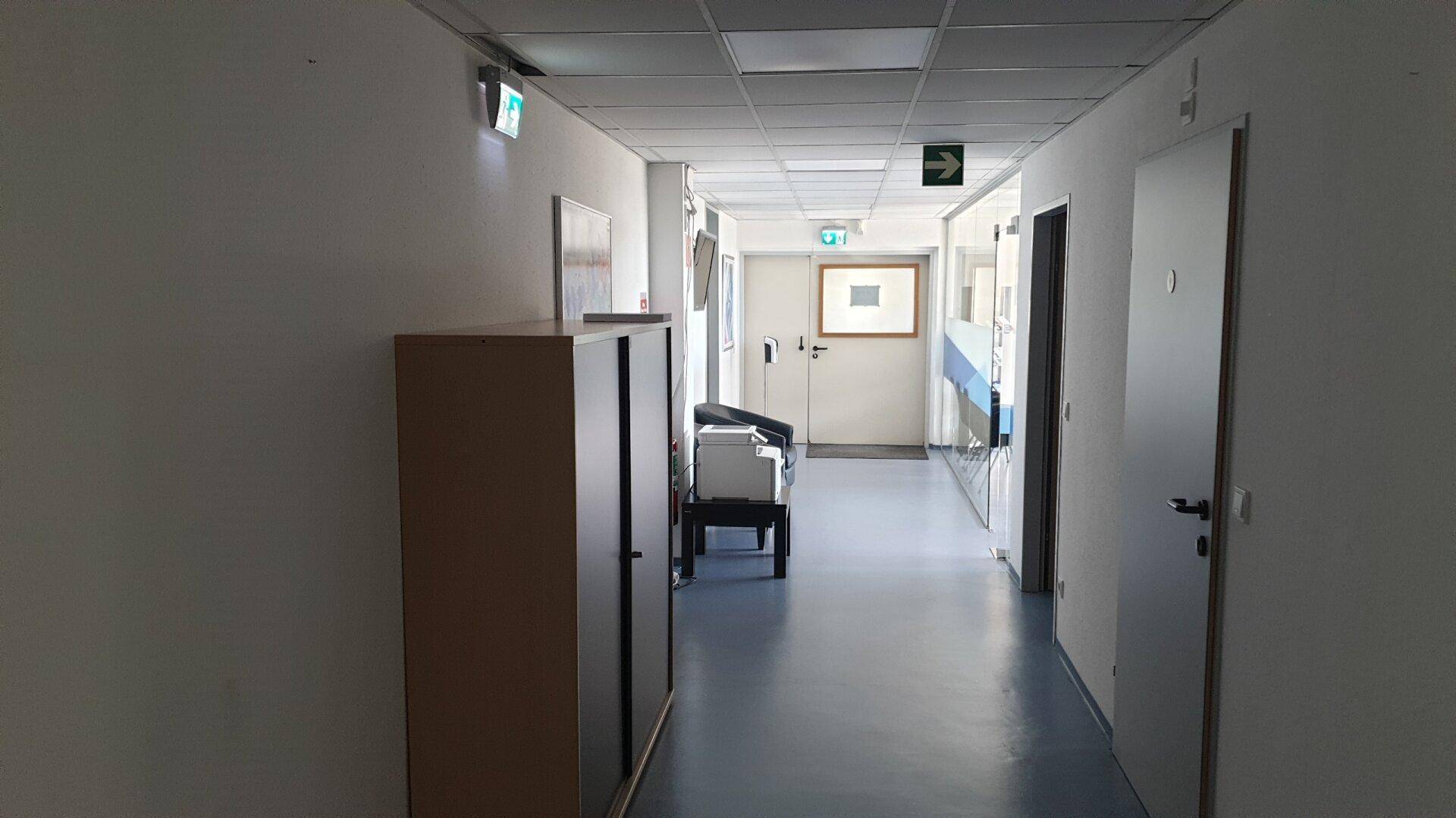 Langer, heller Flur mit Türen zu verschiedenen Räumen und Deckenbeleuchtung.