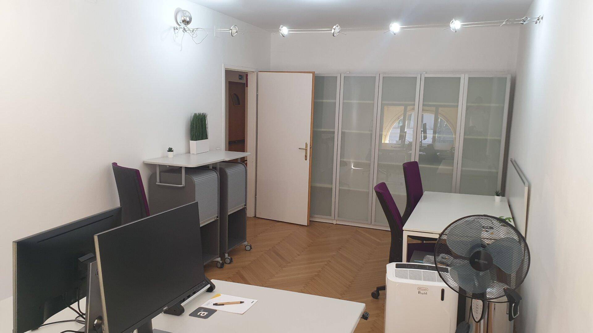 Funktionaler Bürobereich mit mehreren Arbeitsplätzen, Schränken und einem Ventilator für Komfort.