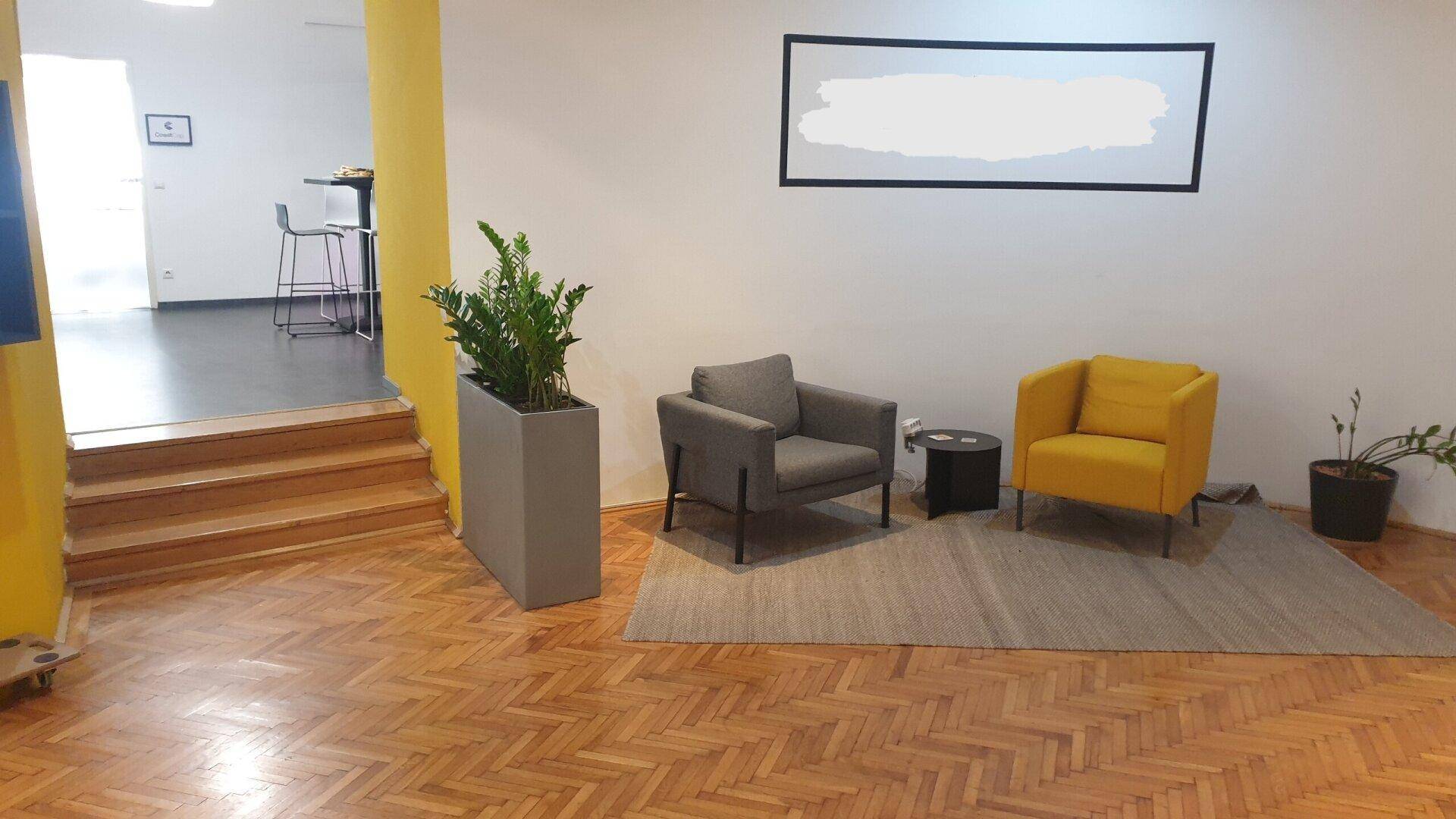 Gemütlicher Loungebereich mit bequemen Sesseln, Teppich und Pflanzen, ideal für Pausen.