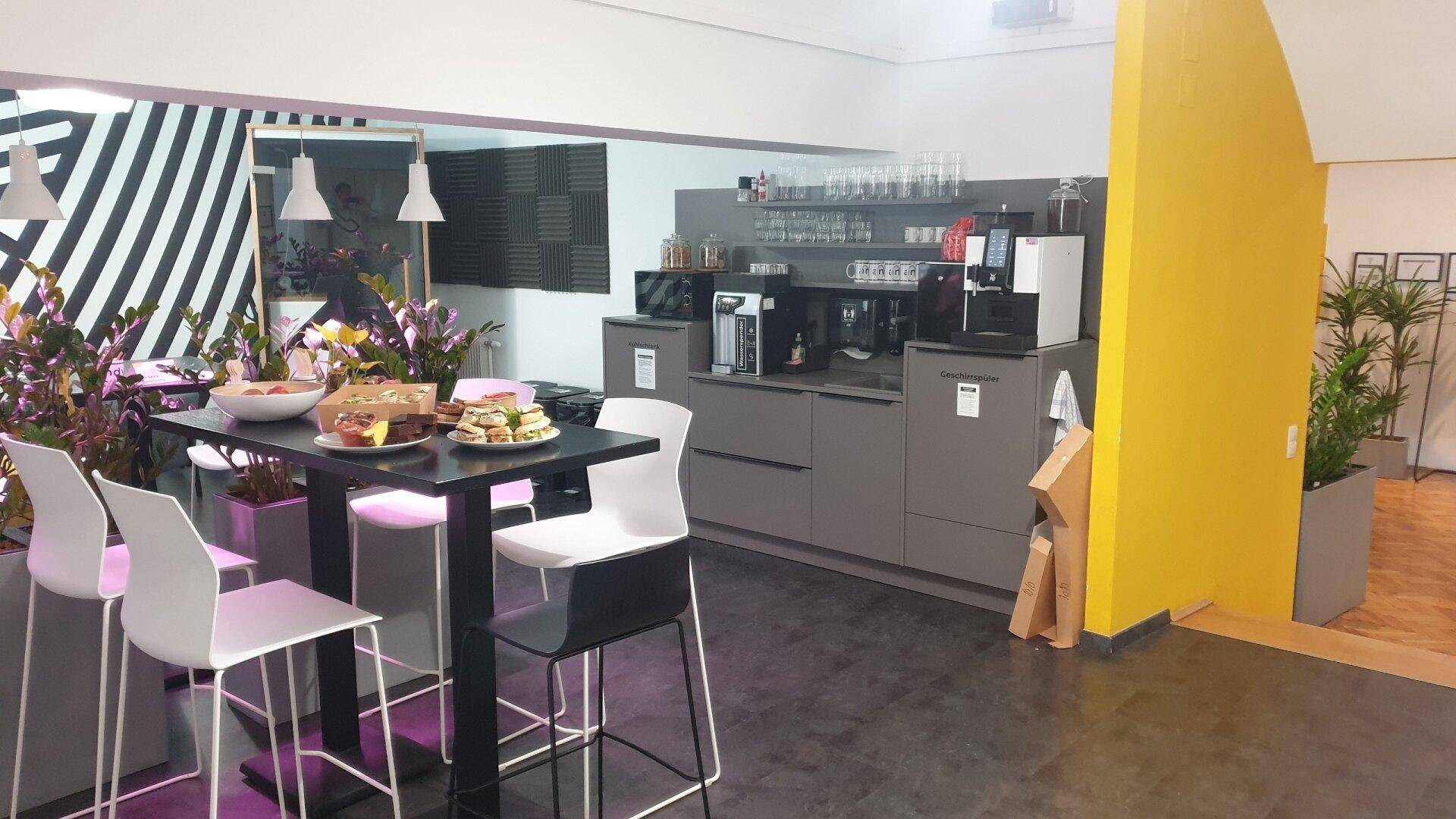 Moderne Teeküche mit Bartisch, Kaffeemaschinen und Stauraum, perfekt für Mitarbeiterpausen.