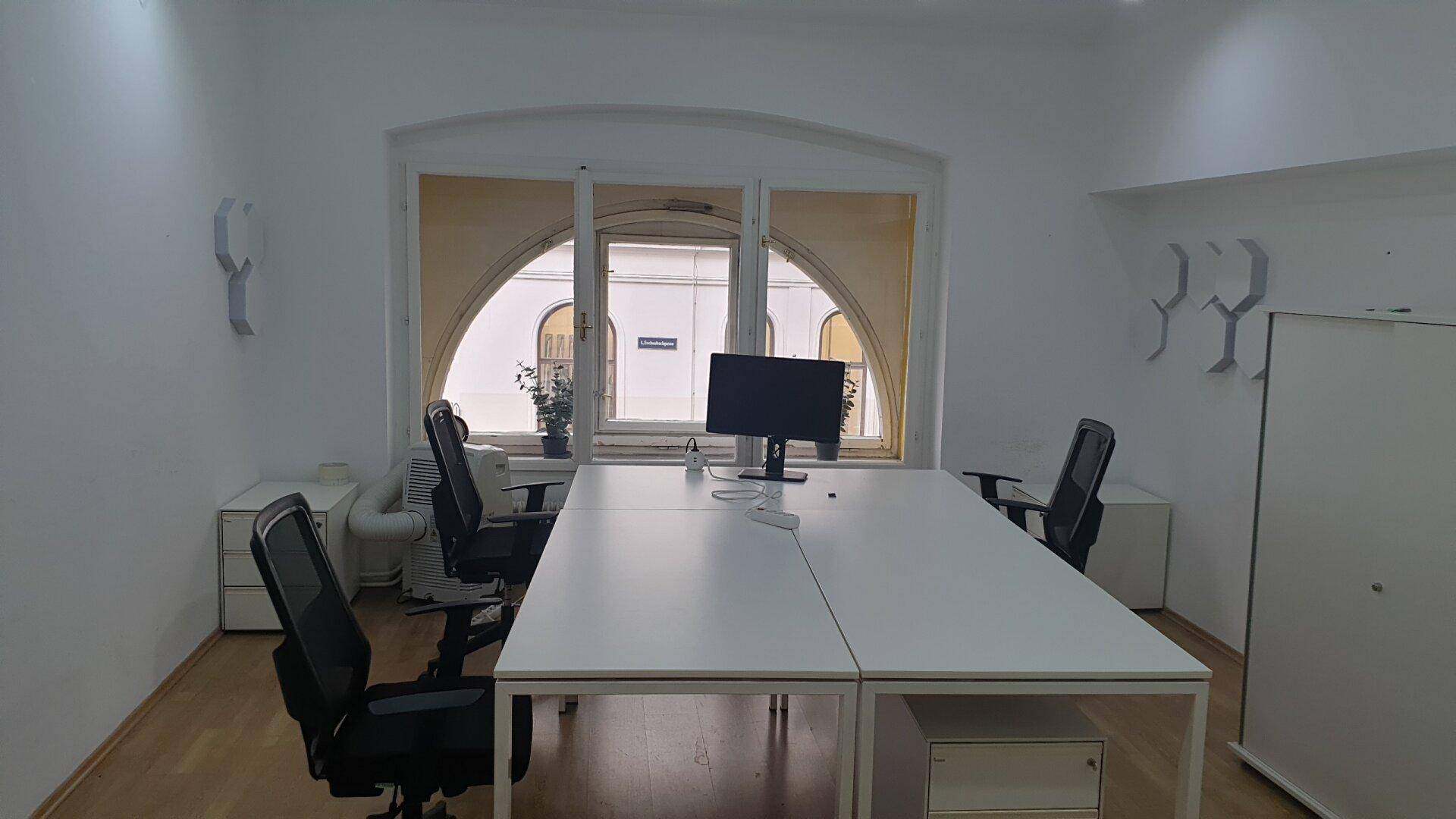 Helles Büro mit modernen weißen Schreibtischen, ergonomischen Stühlen und großen Bogenfenstern, die viel Tageslicht hereinlassen.