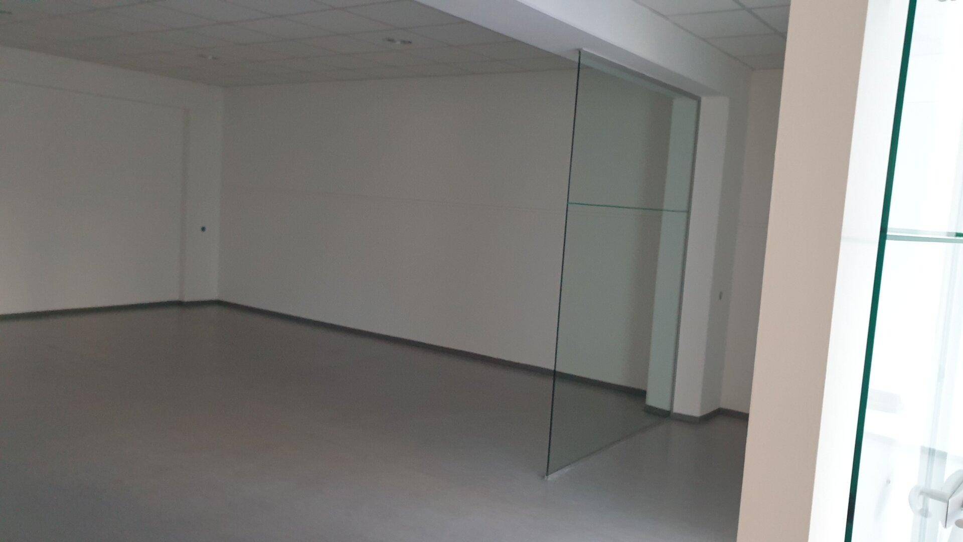 Großer, offener Gewerberaum mit hellen Wänden und einer modernen Glasabtrennung.
