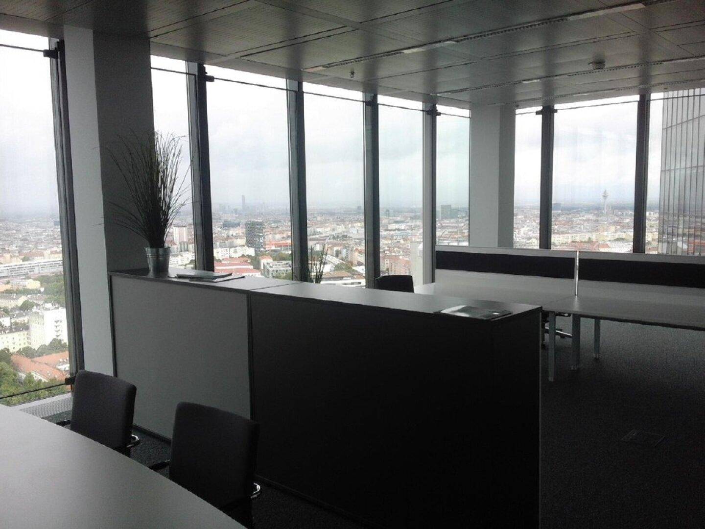 Großraumbüro mit mehreren Arbeitsplätzen und beeindruckendem Panoramablick über die Stadt.