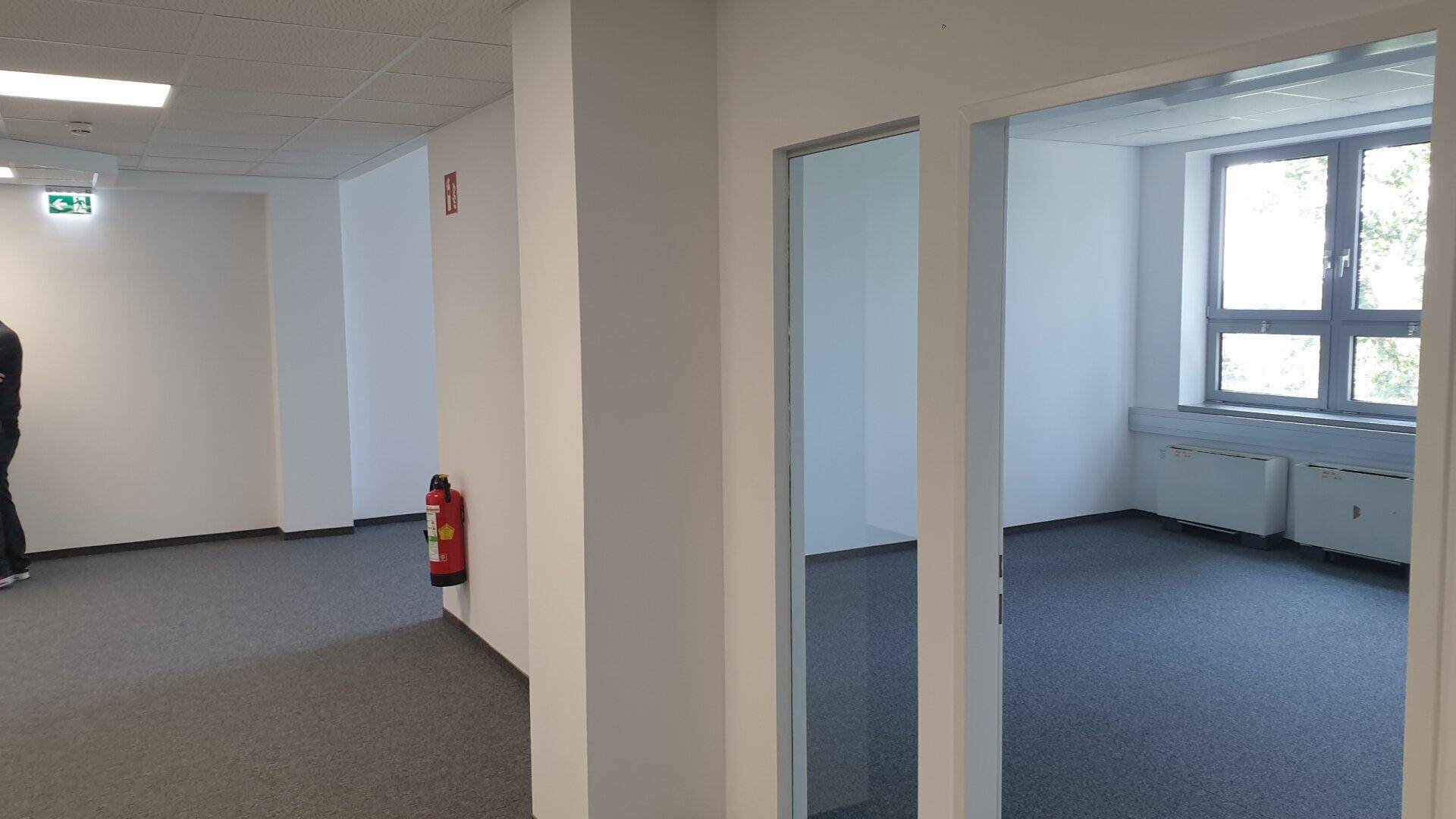 Geräumiger Flur in einem Gewerbeobjekt mit Teppichboden und Zugang zu einem hellen Büroraum.