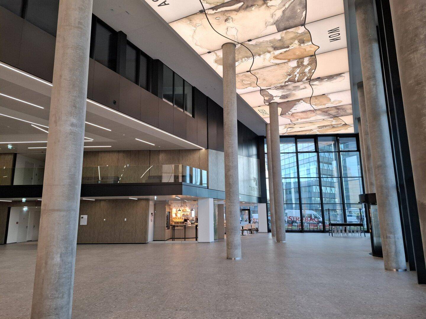 Beeindruckende Lobby mit hohen Decken, massiven Säulen und einer dekorativen Weltkarte an der Decke.