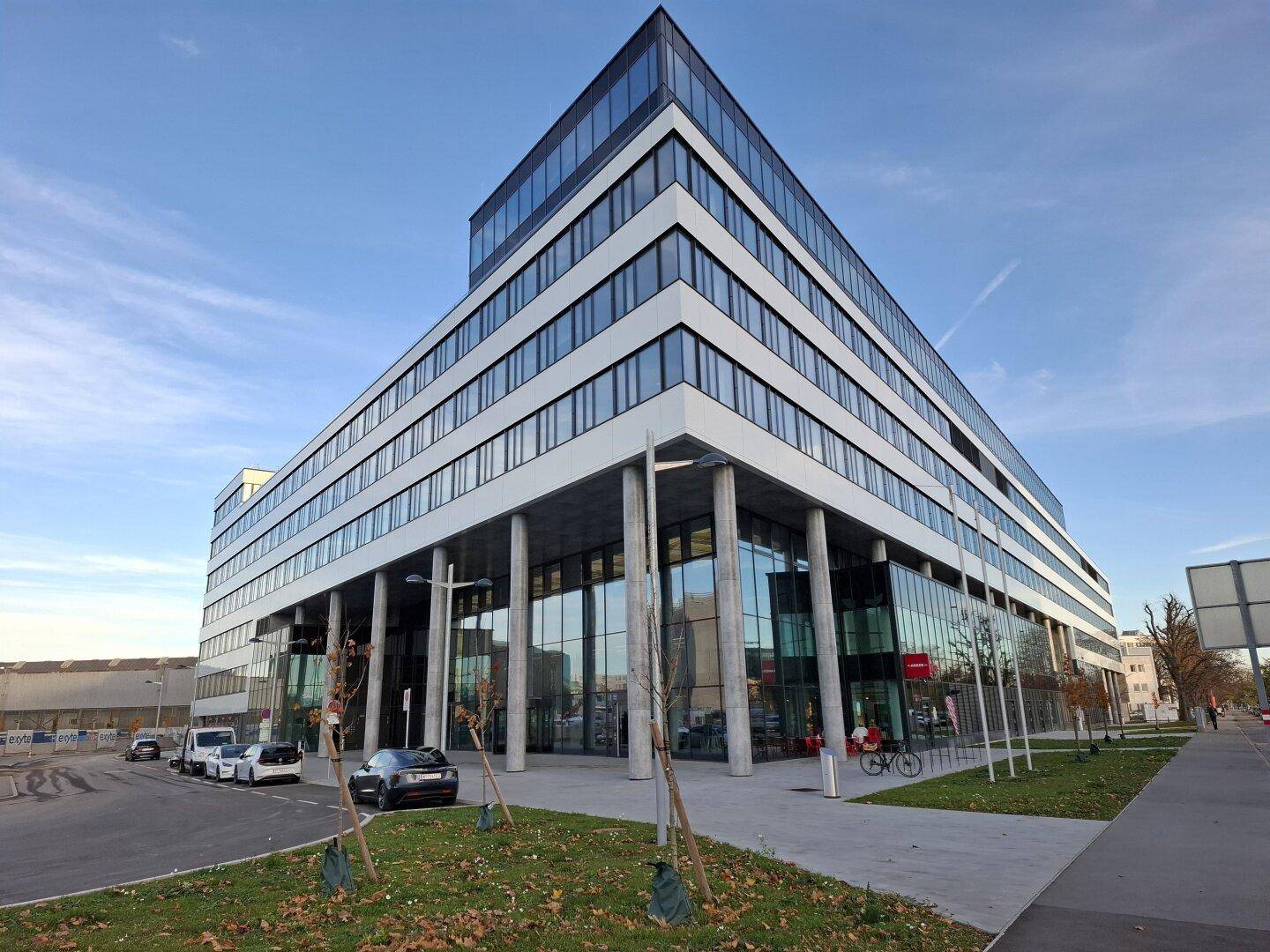 Großes, modernes Bürogebäude mit Glasfassade und klaren Linien, von der Straße aus gesehen.