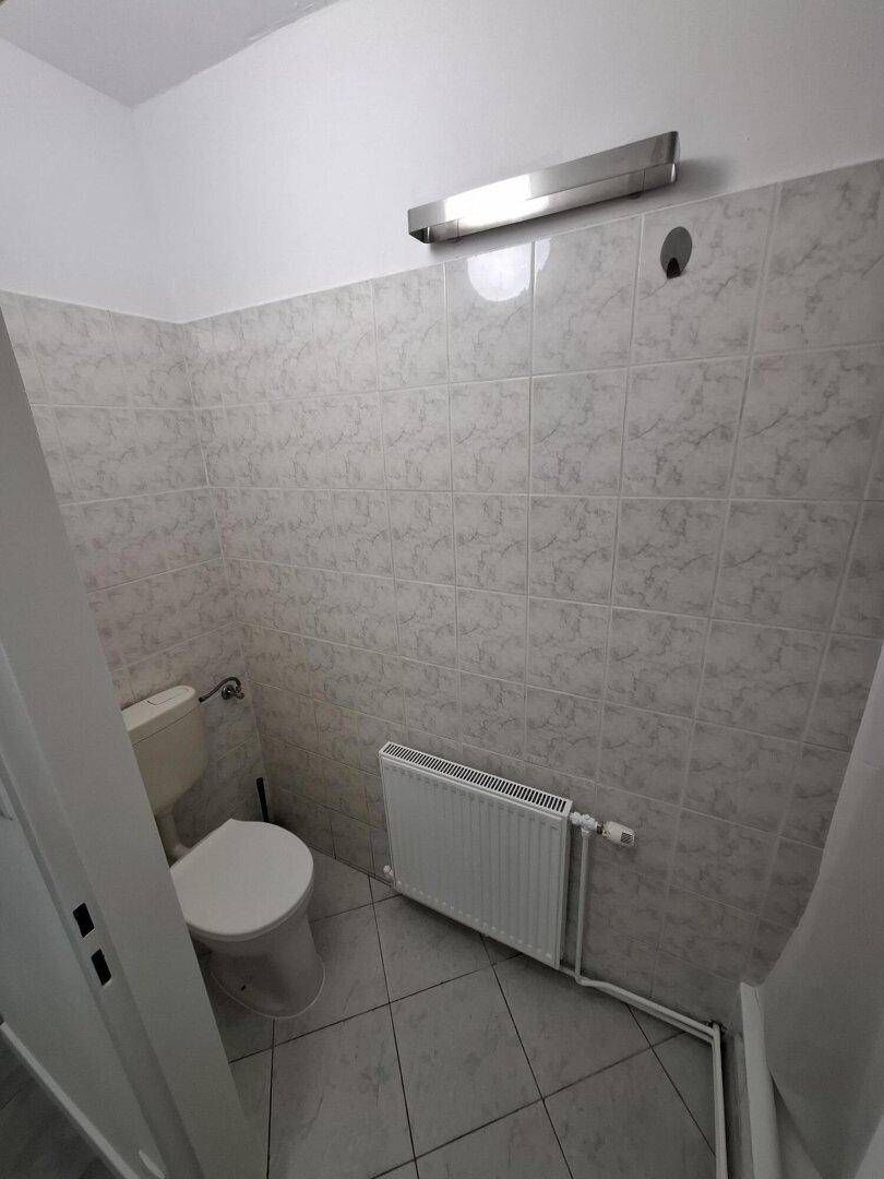 Kleines Badezimmer oder Gäste-WC mit Toilette, Heizkörper und hell gefliesten Wänden.