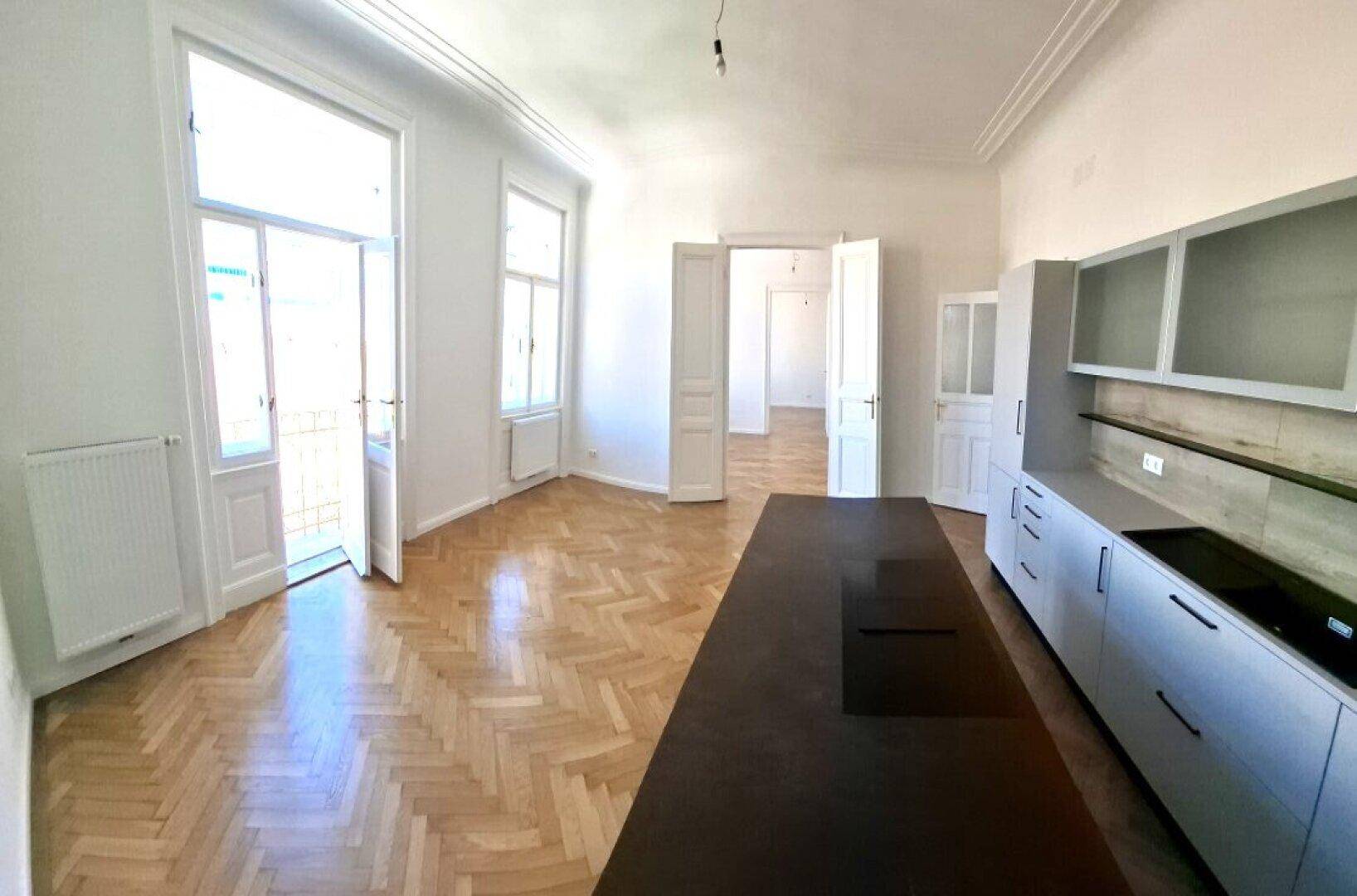 Offene Küche mit moderner Kücheninsel, Einbauschränken und Zugang zu einem französischen Balkon.