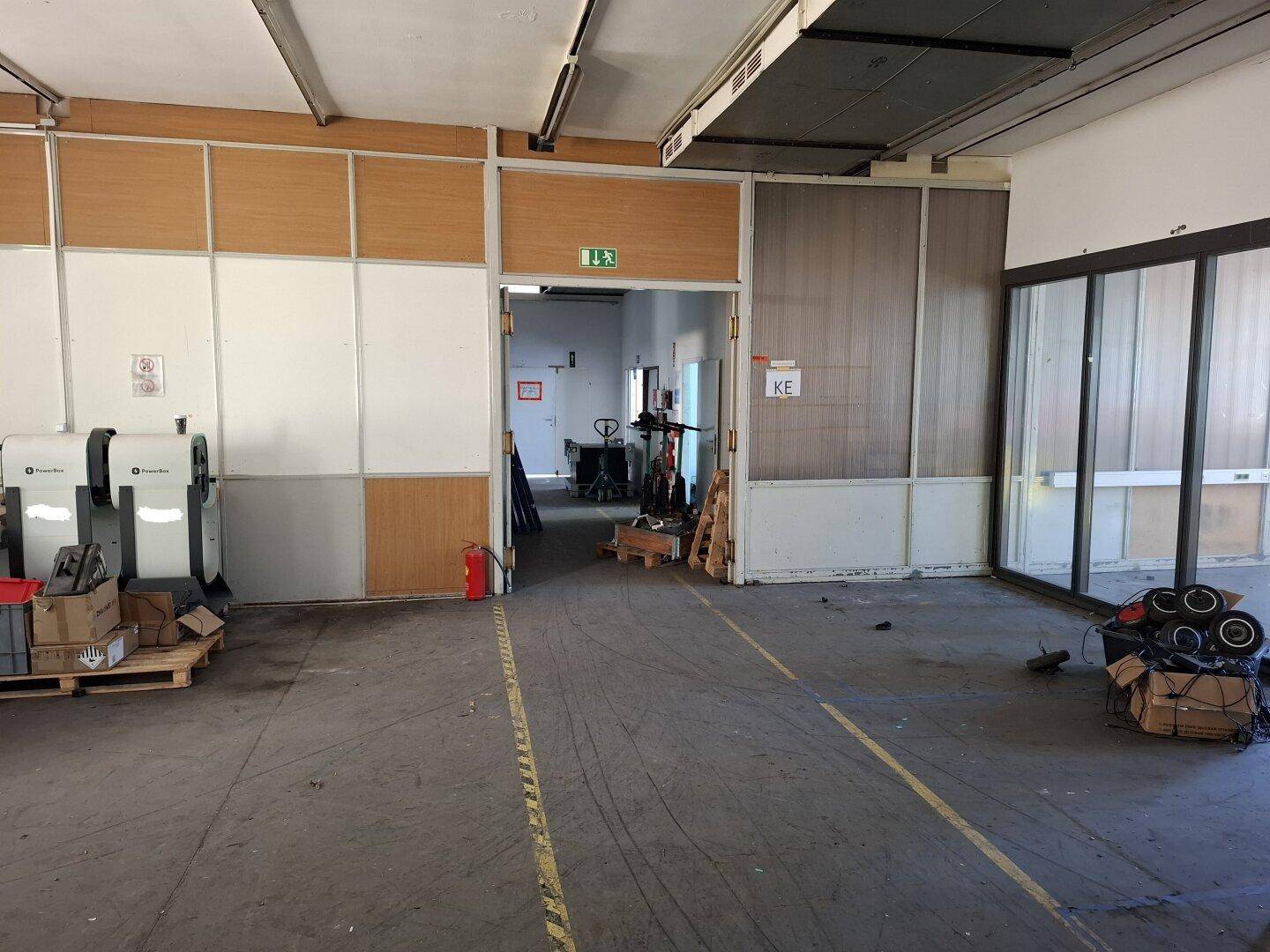 Ansicht eines Industrieraums mit Betonboden, modularen Trennwänden und einem offenen Durchgang zu einem weiteren Bereich.