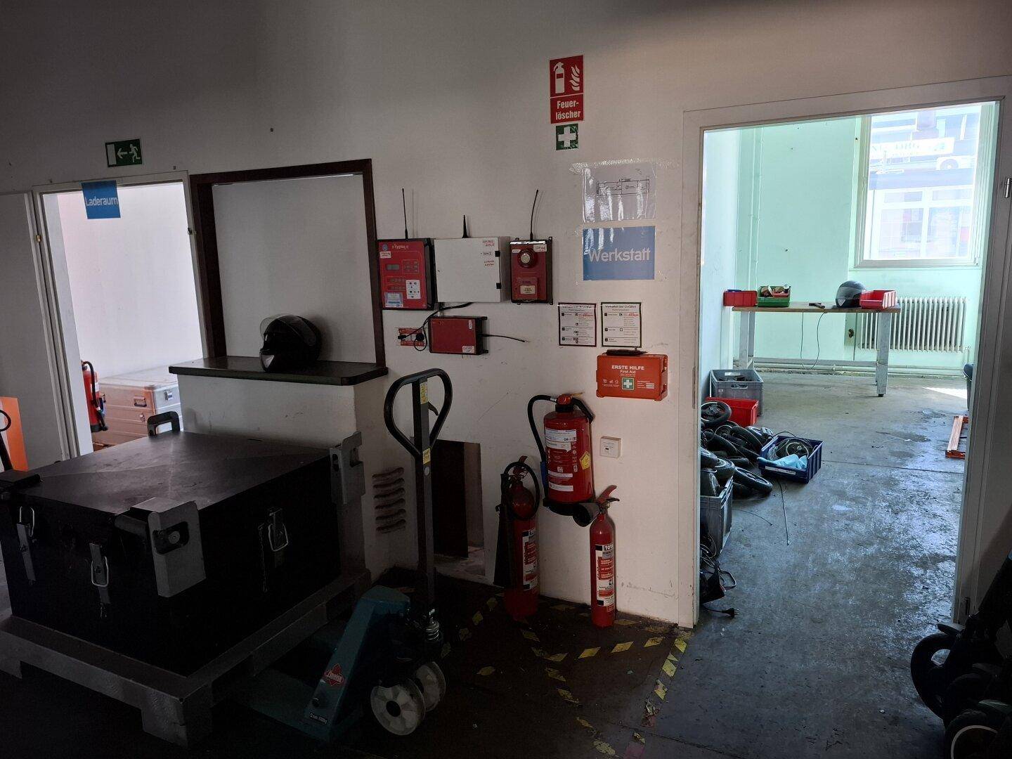 Bereich mit einer Theke und verschiedenen Installationen, daneben ein offener Durchgang zu einem weiteren Arbeitsraum.