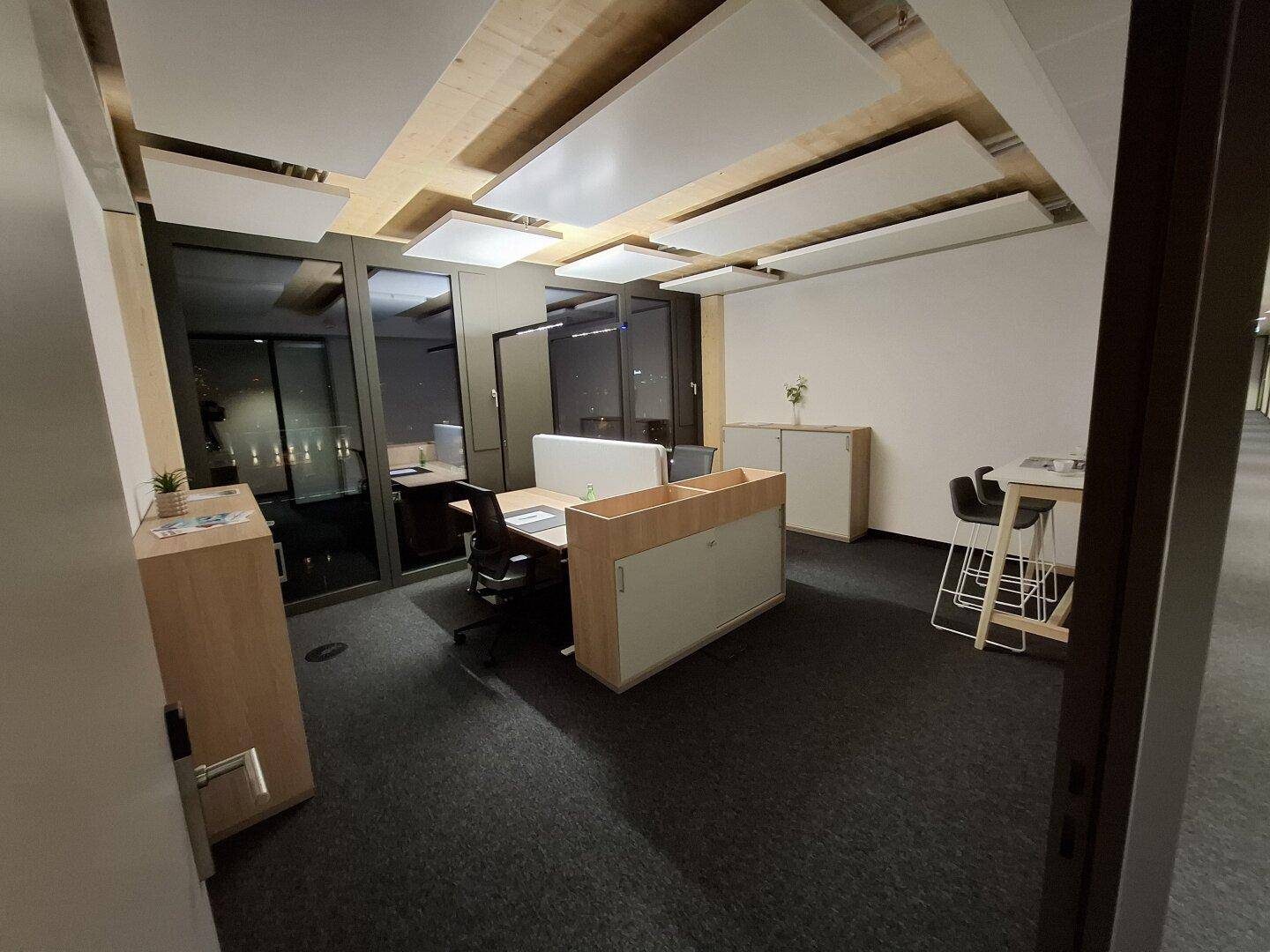 Geräumiges, modernes Büro mit ergonomischen Arbeitsplätzen und schallabsorbierenden Deckenpaneelen.