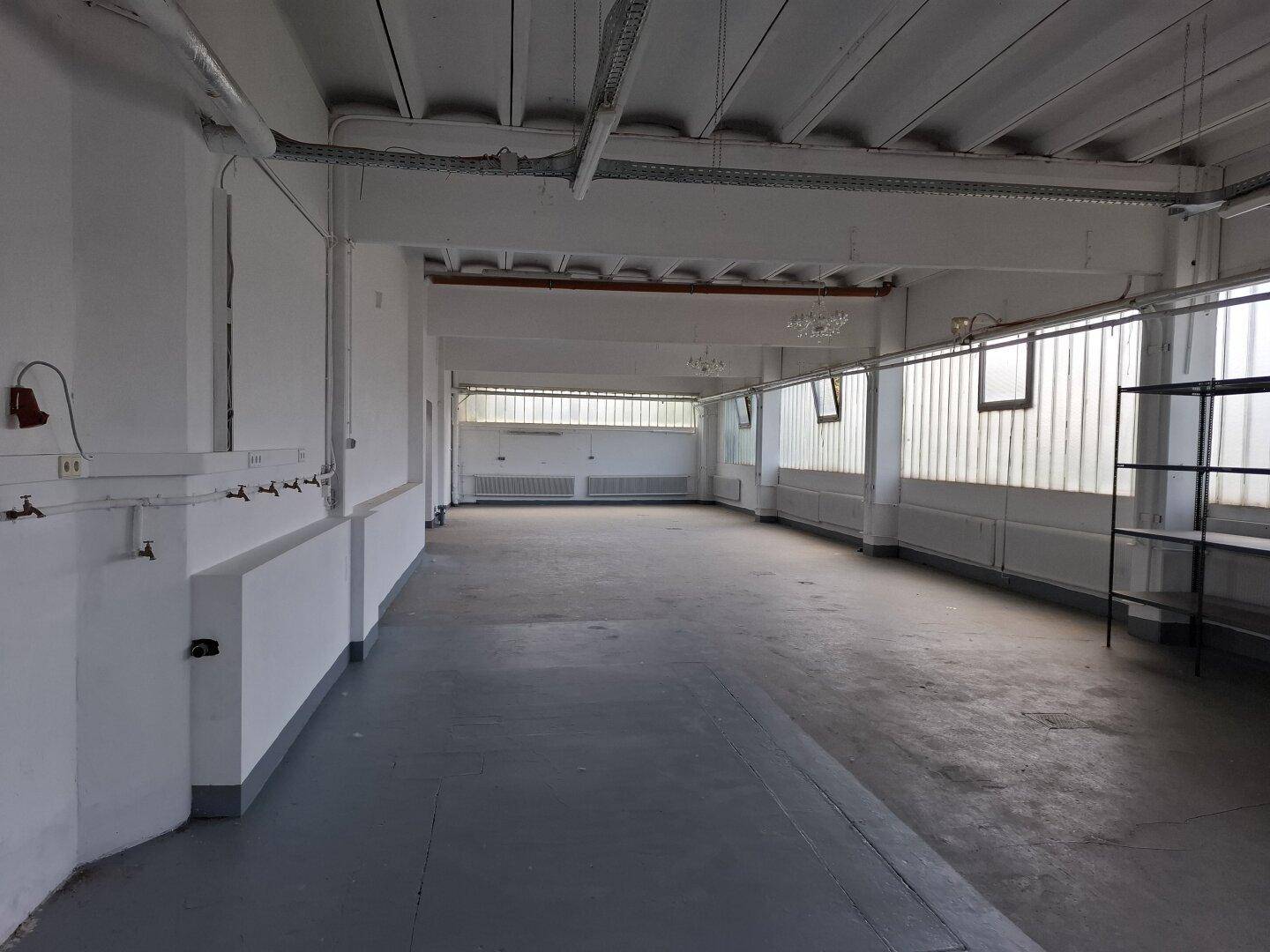 Geräumiger Bürobereich mit langen Fensterfronten, Heizkörpern und sichtbaren Deckenbalken.