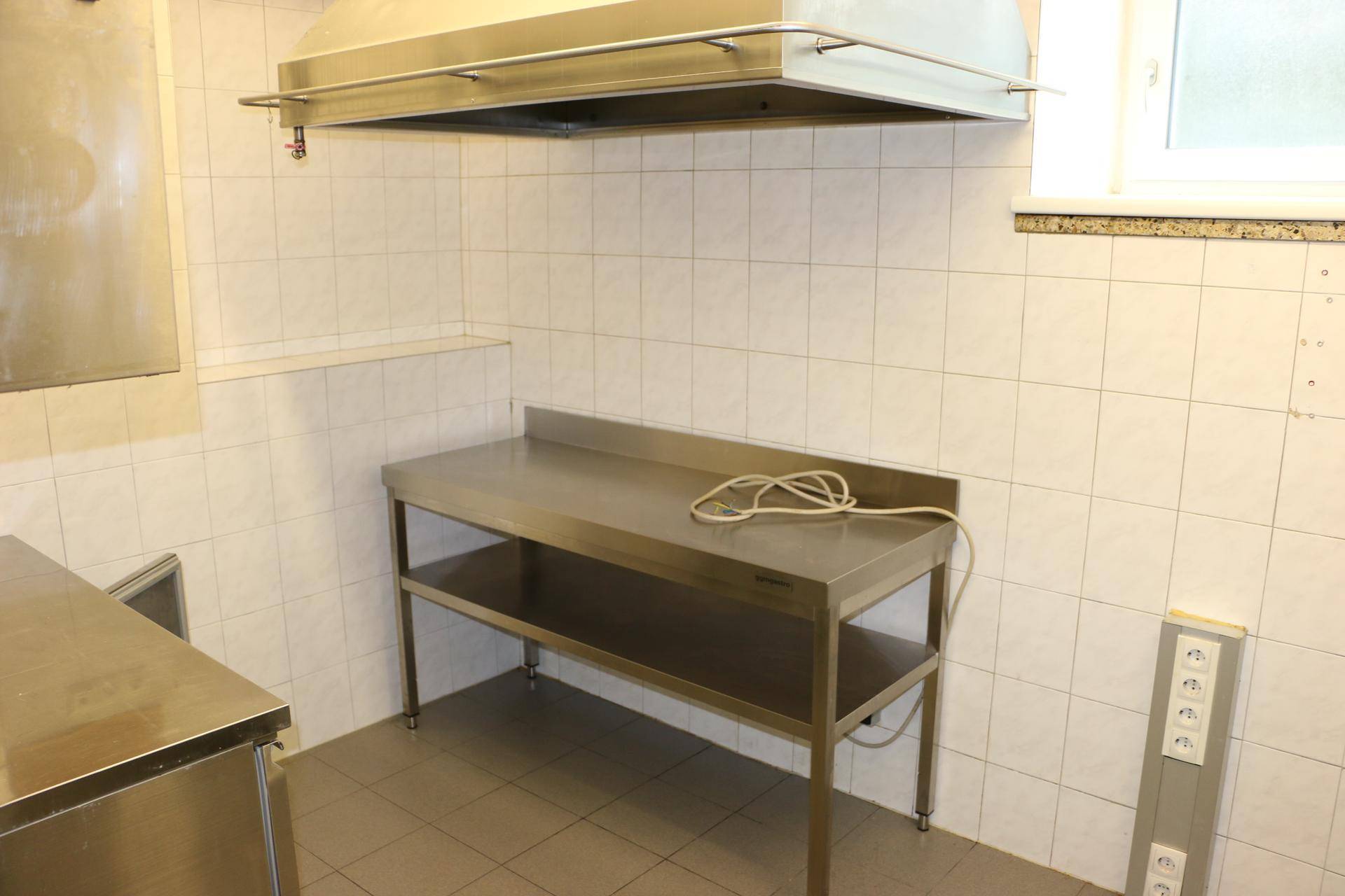 Professionelle Küche mit Edelstahlarbeitsflächen und Fliesen an Wänden und Boden.