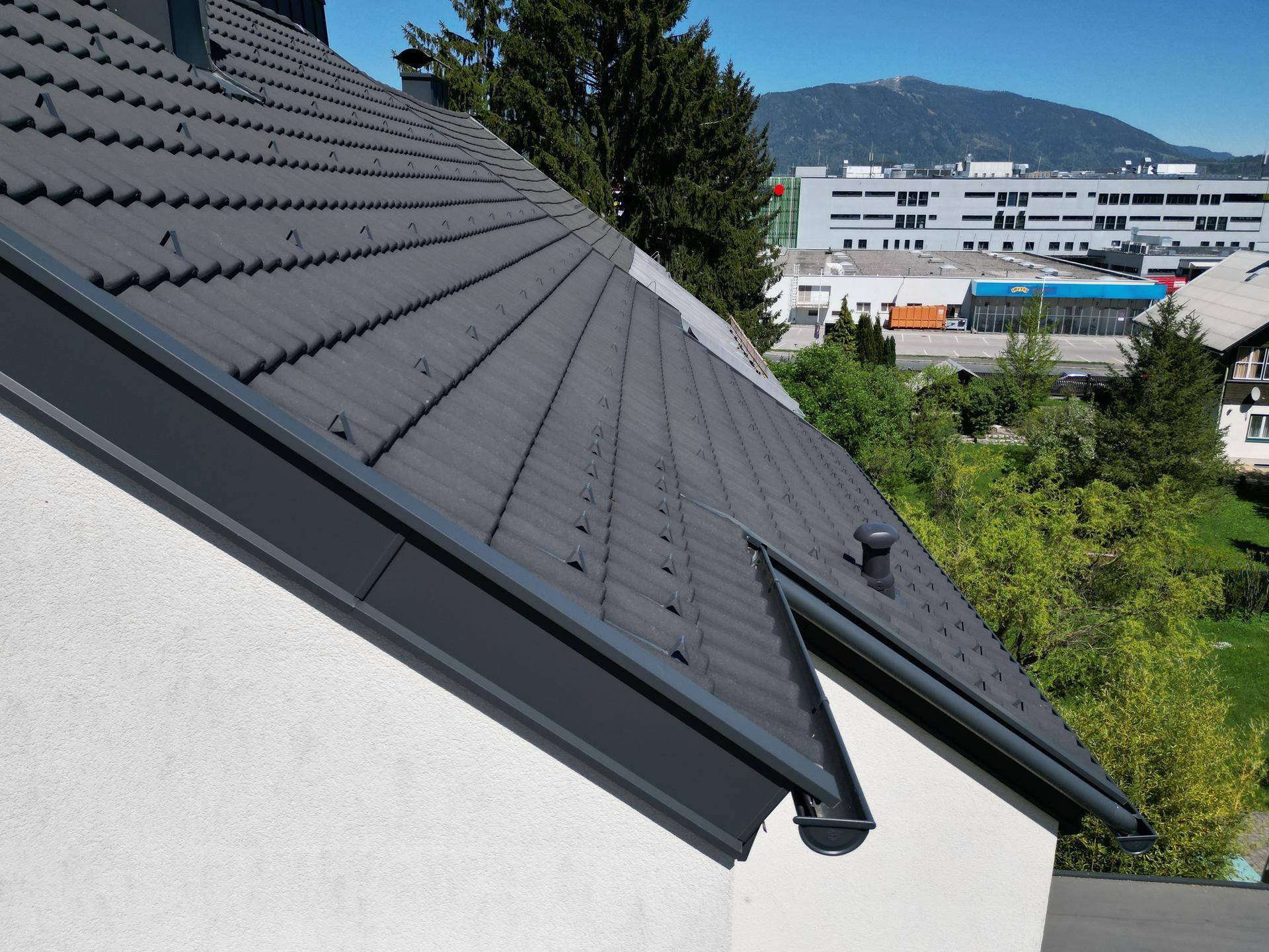 Nahaufnahme des gepflegten Ziegeldachs mit Blick auf die umliegende Landschaft und Berge.