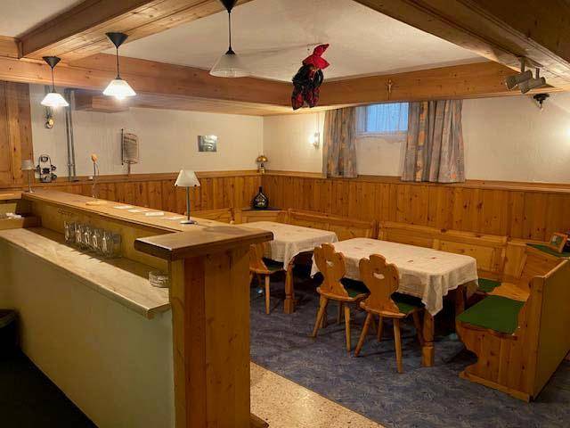Rustikaler Kellerraum mit Bar, Holzvertäfelung und gemütlichen Sitzecken für gesellige Runden.