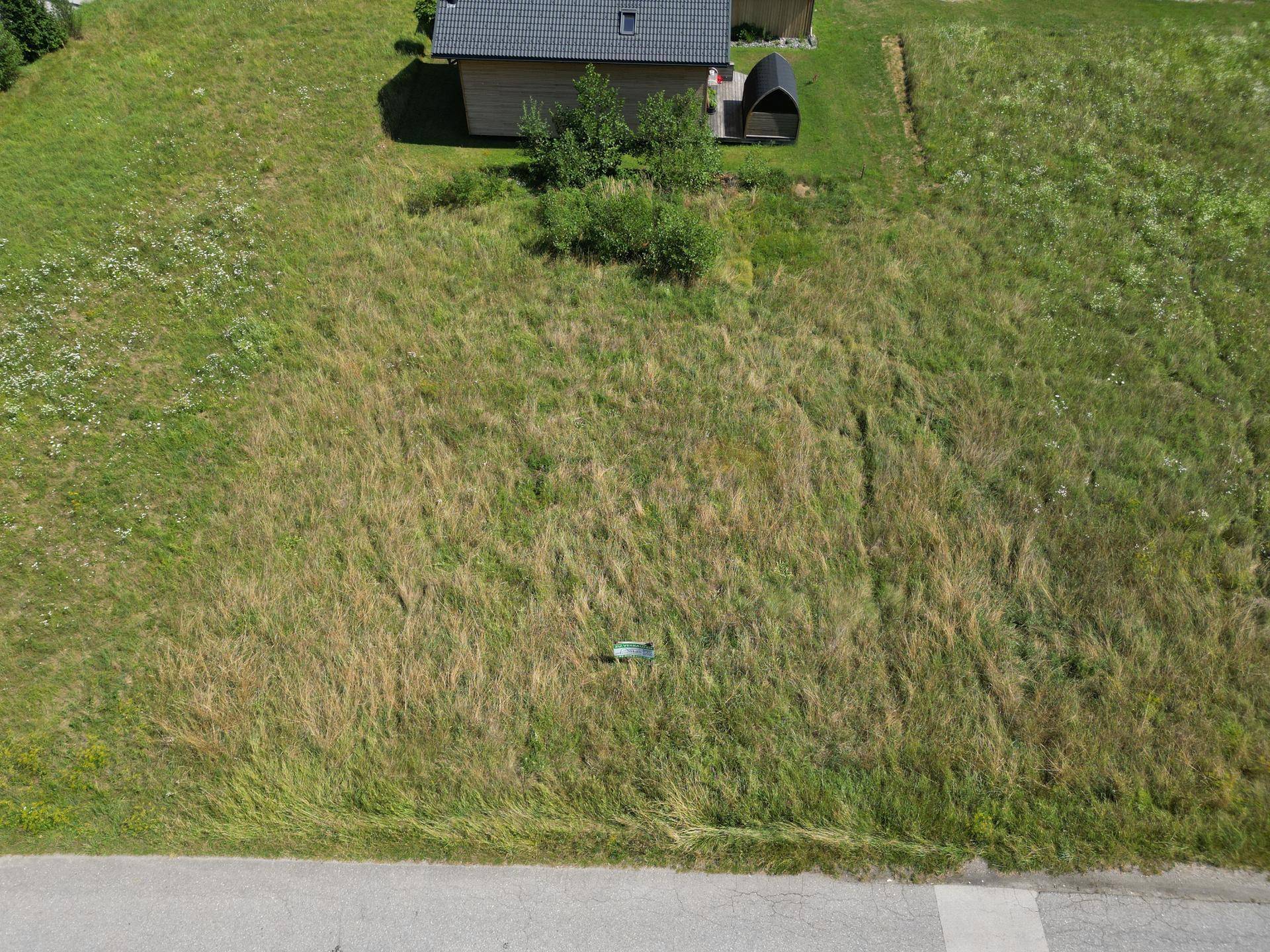 Nahaufnahme aus der Vogelperspektive eines grünen Grundstücks mit einem modernen Nebengebäude.