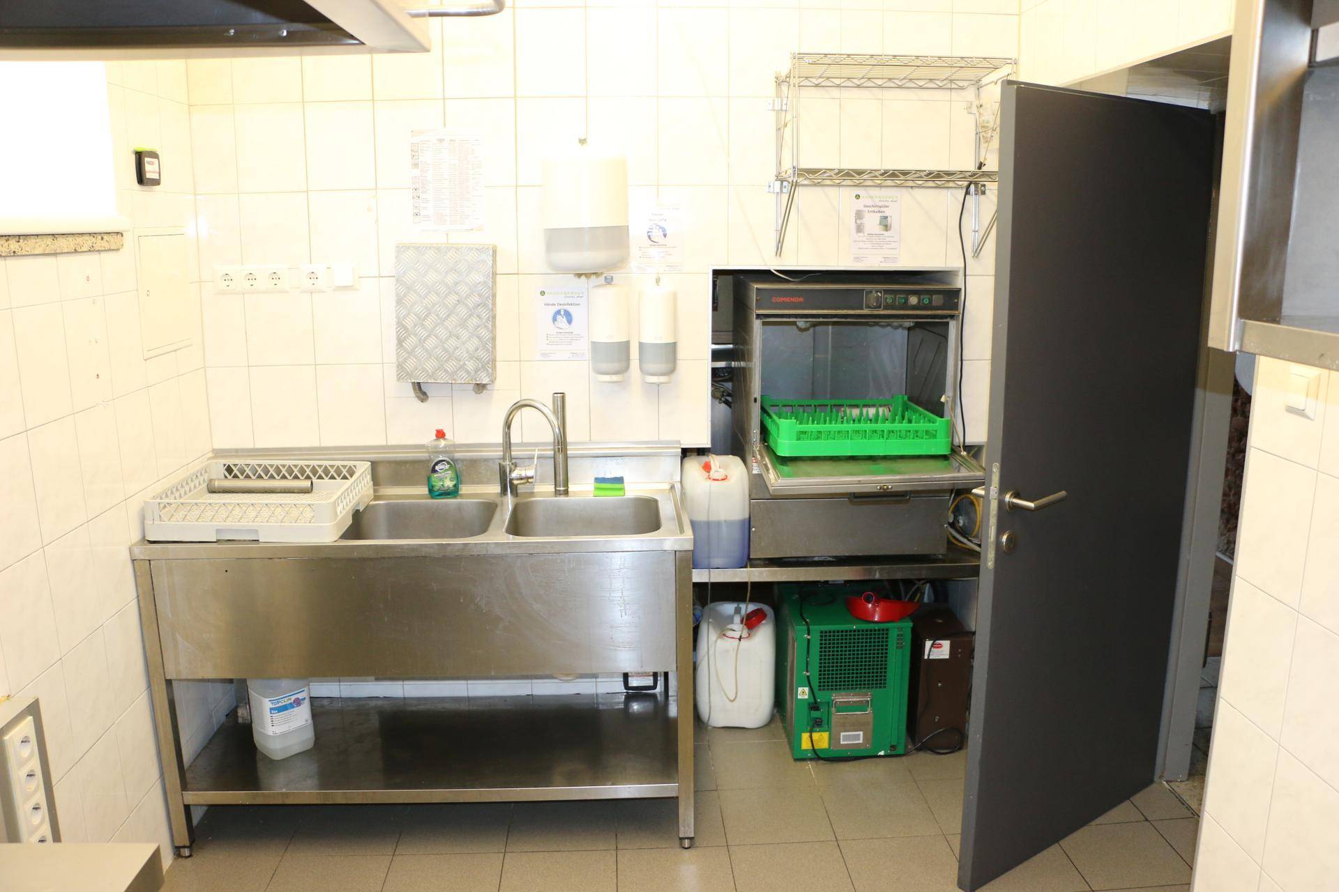 Spülbereich in der Gewerbeküche mit Doppelspüle und professioneller Spülmaschine.