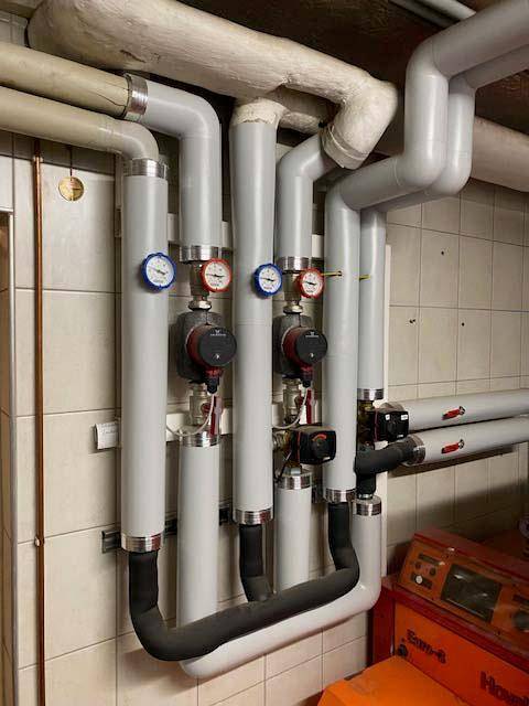 Detailansicht der Heizungsrohre und Pumpen in einem gut organisierten Technikraum.