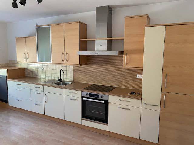 Einbauküche mit hellen Holzfronten, integriertem Backofen und Dunstabzugshaube.