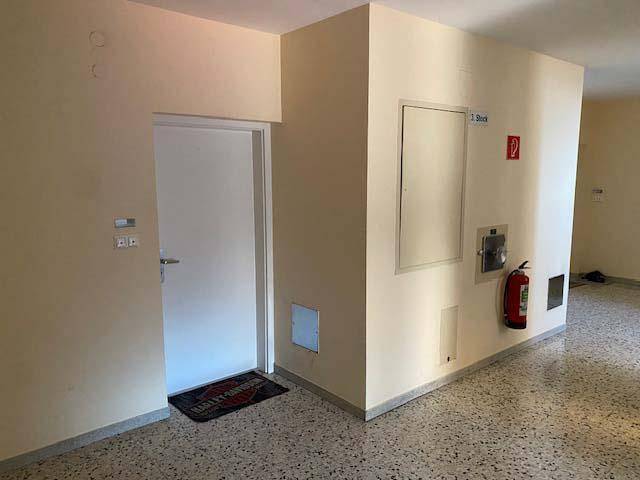 Eingangsbereich im Gebäude mit Terrazzoboden, Brandschutz und Zugang zur Wohnung.