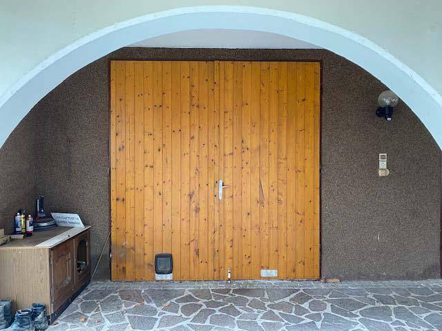 Großes hölzernes Garagentor unter einem gemauerten Bogen, Teil des Untergeschosses.