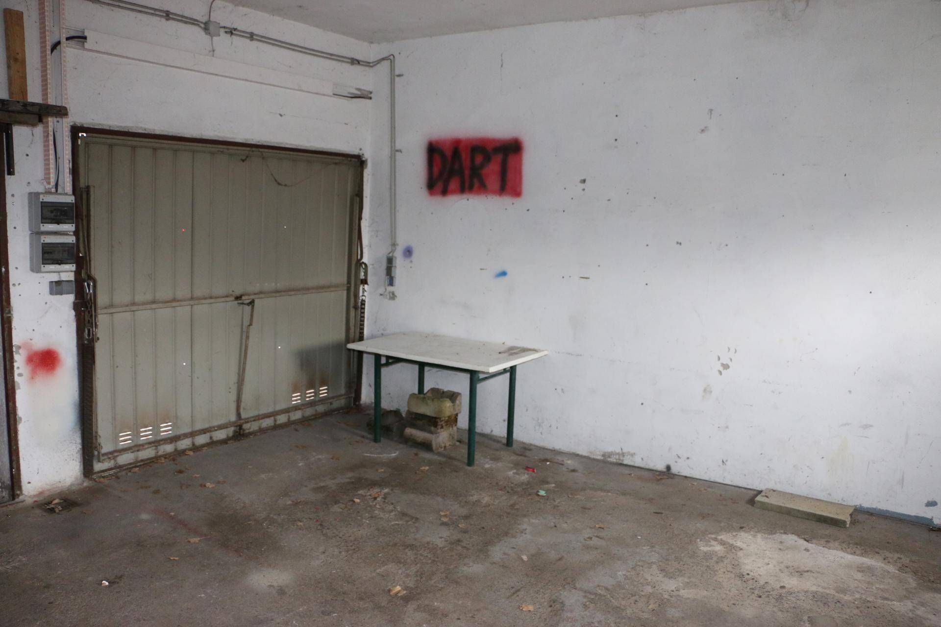Garagenraum mit Rolltor, Betonboden und einer einfachen Werkbank.