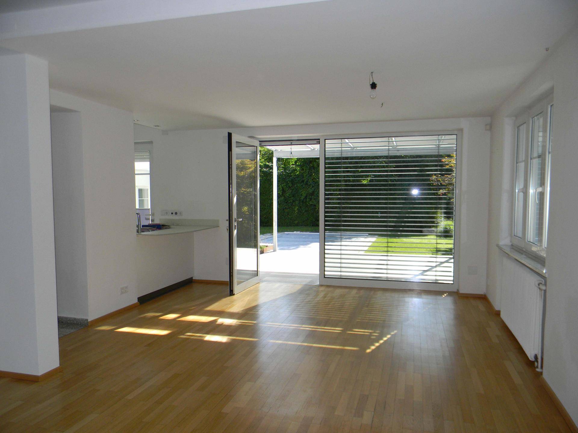 Helles Wohnzimmer mit Parkettboden und direktem Zugang zur Terrasse und zum Garten.