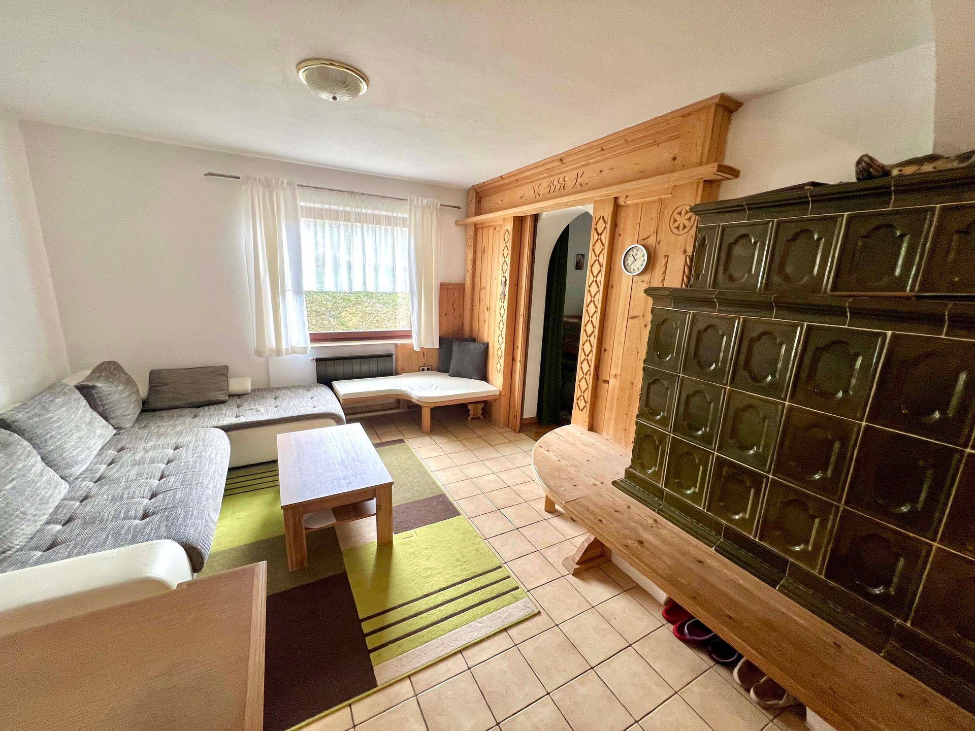 Gemütliches Wohnzimmer mit traditionellem Kachelofen, Holzvertäfelung und bequemer Sitzecke.