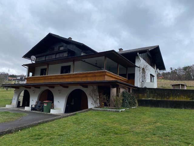 Außenansicht des Hauses mit überdachtem Eingangsbereich, Garagenbögen und großem Balkon im Obergeschoss.