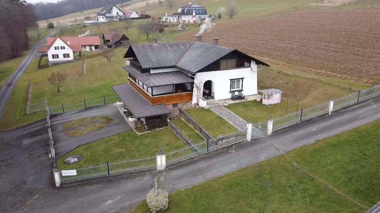 Luftaufnahme des Haupthauses mit gepflegtem Vorgarten, Zufahrt und ländlicher Umgebung.