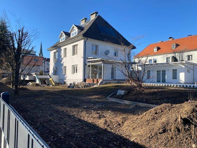 Seitenansicht des Hauses mit Dachgauben, Solarpaneelen und einem Gartenbereich.