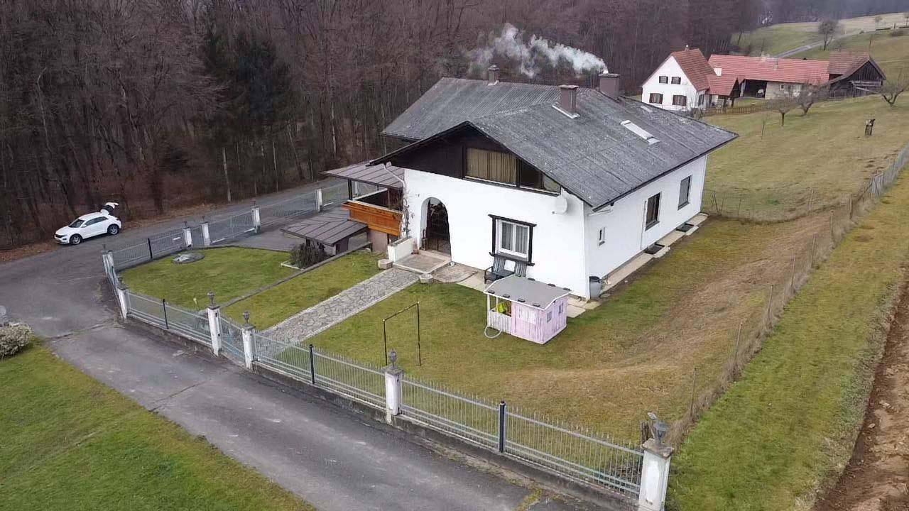 Luftaufnahme des Haupthauses mit Vorgarten, Zufahrt und einem geparkten Auto in ländlicher Umgebung.