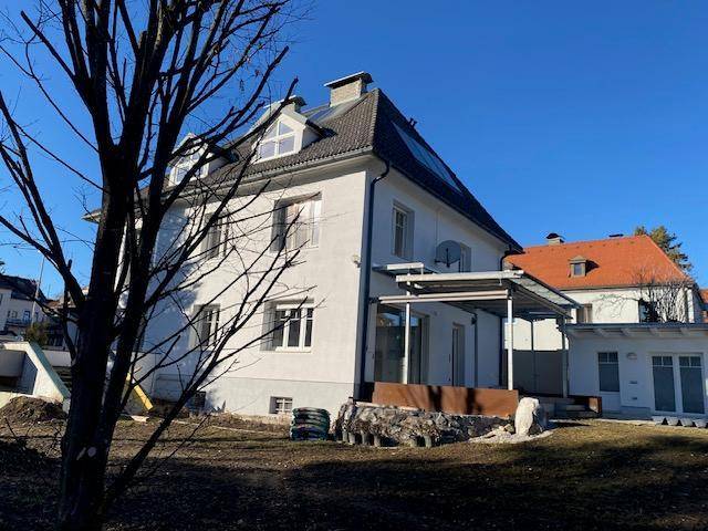 Seitenansicht des Hauses mit Dachgauben, Solarpaneelen und einem Gartenbereich.