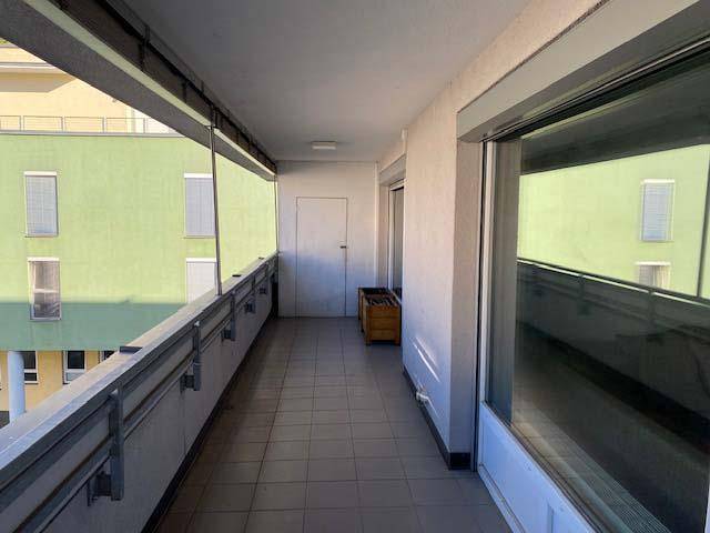 Langer, gefliester Balkon mit Metallgeländer und Blick auf die gegenüberliegenden Gebäude.