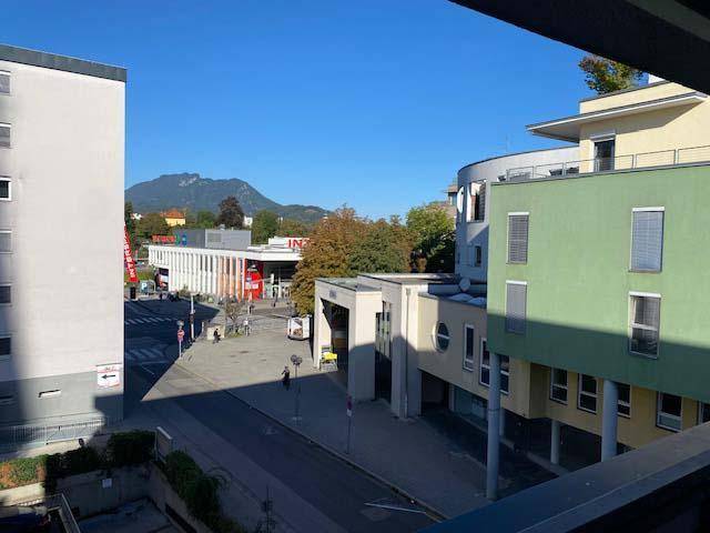 Ausblick auf die umliegende Stadtlandschaft mit Geschäften und Bergen im Hintergrund.