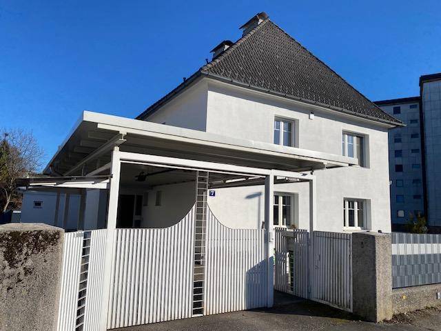 Vorderansicht des Hauses mit Carport, weißem Zaun und gepflegter Fassade.