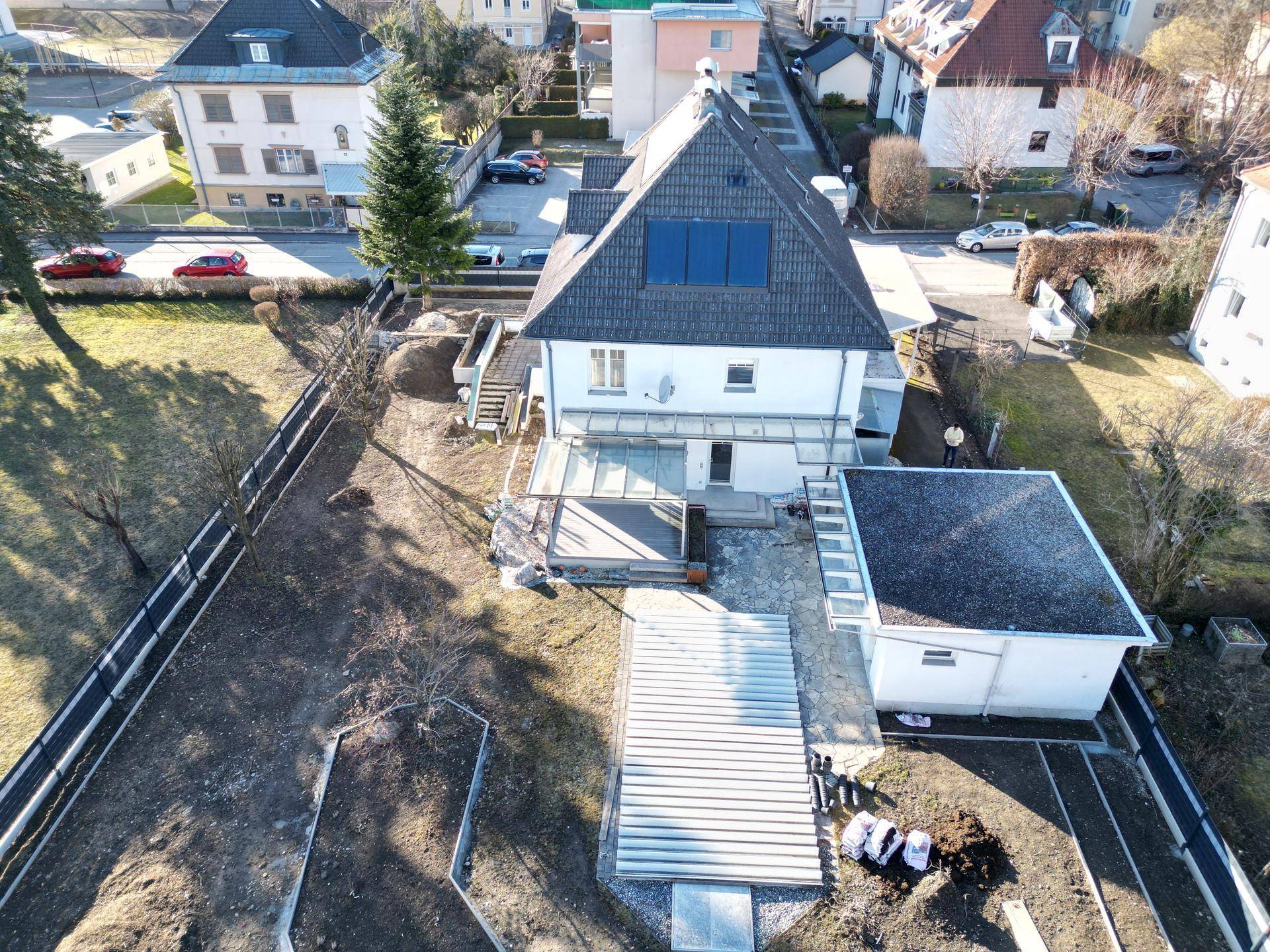 Luftaufnahme des Hauses mit Dach, Solarpaneelen, Terrasse und Gartenbereich in einer Wohngegend.