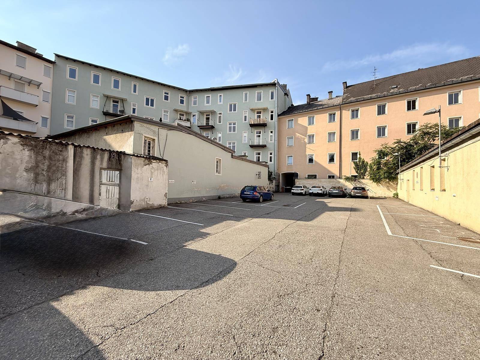 Außenparkplatz mit mehreren geparkten Autos und hohen Wohngebäuden im Hintergrund.